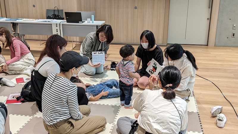 読み聞かせを行う学生と絵本に興味津々の子ども