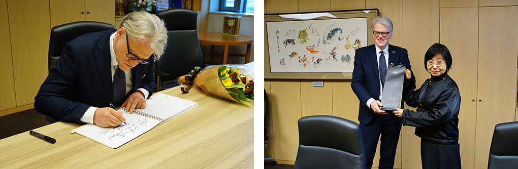 （左）サインに応じるジーカス大使　（右）プレゼント交換をするジーカス大使と篠原学長